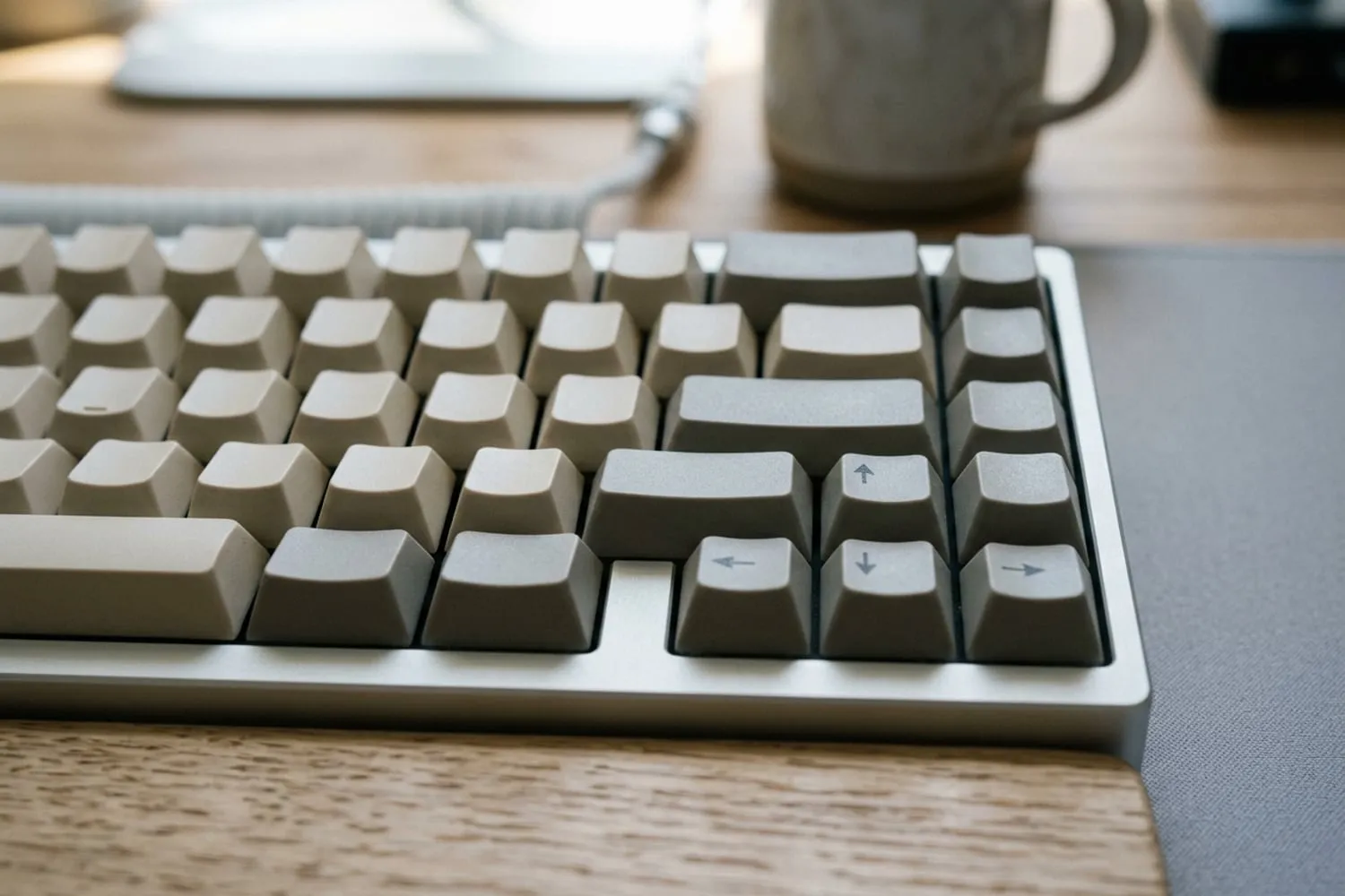 The right-hand edge of a compact 65% keyboard close up: a single column of keys running down beside the wide keys at the row ends, the four arrow keys tucked into the bottom corner, every keycap blank