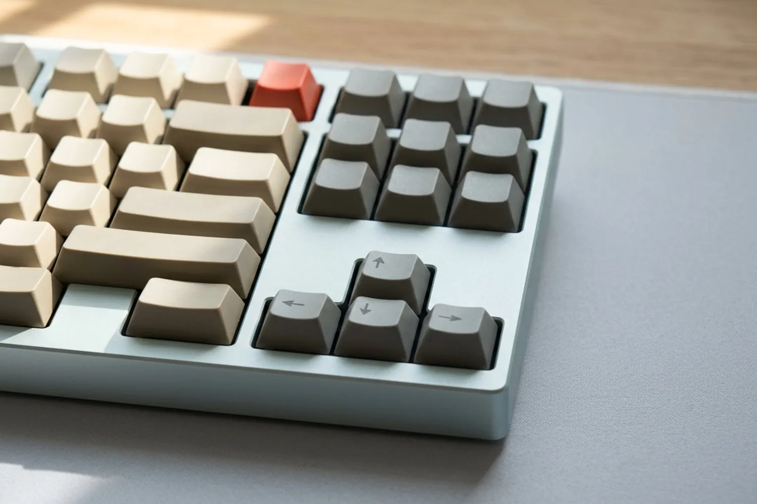 The arrow keys of a tenkeyless keyboard up close: four grey keys in an inverted T, the block of six navigation keys above them, beige letter keys to the left, every keycap blank